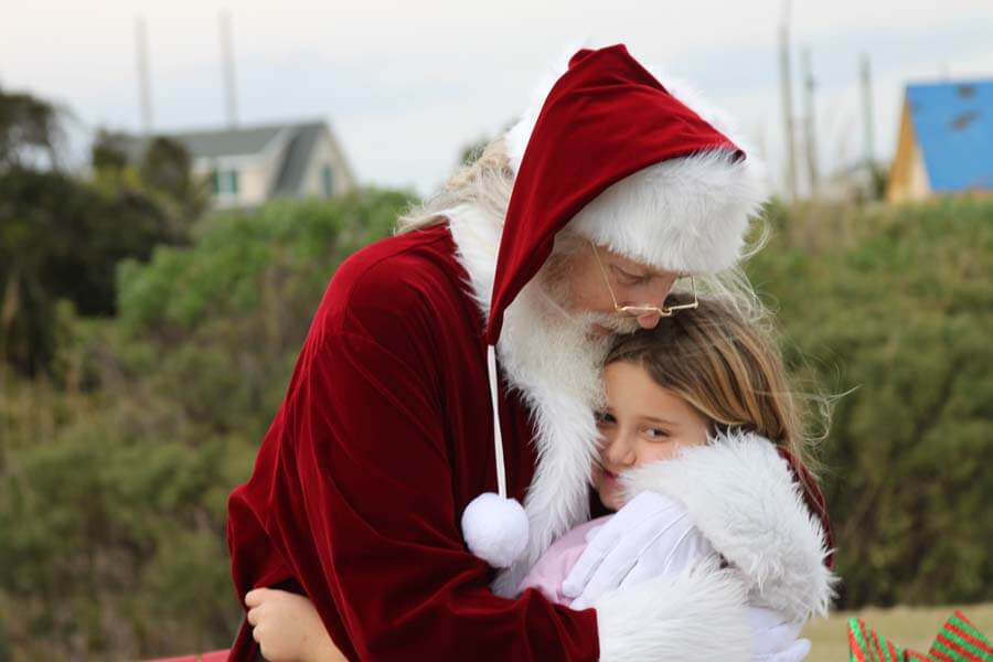 Santa outdoors hugging child